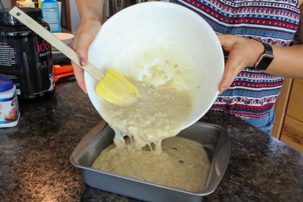Pouring baked oatmeal mixture into pan.